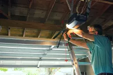 A man using a ladder to fix a garage door opener