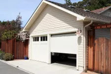 A white garage door with a wooden fence in the background