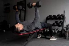 Lying man on a beanch doing weights