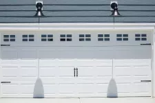 White double garage door with windows and decorative hardwares on a blue house
