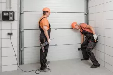 Two men repairing a garage door