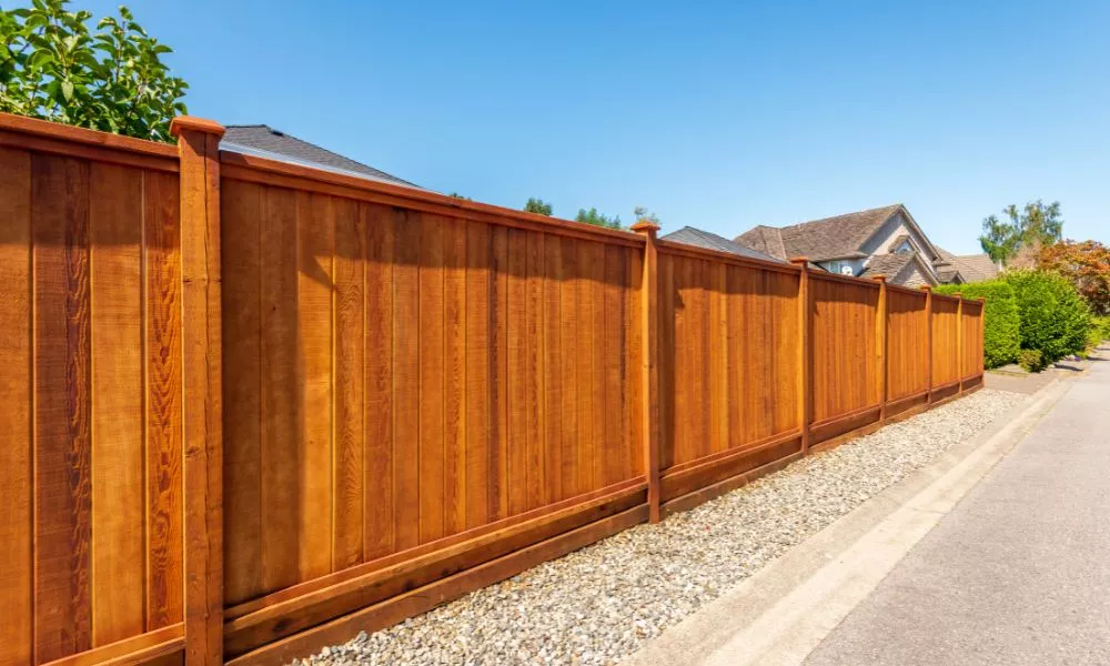 A gravel driveway leading to a wooden fence