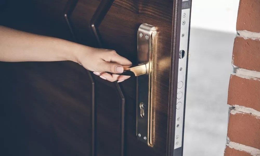 A person's hand on a handle that opens the door