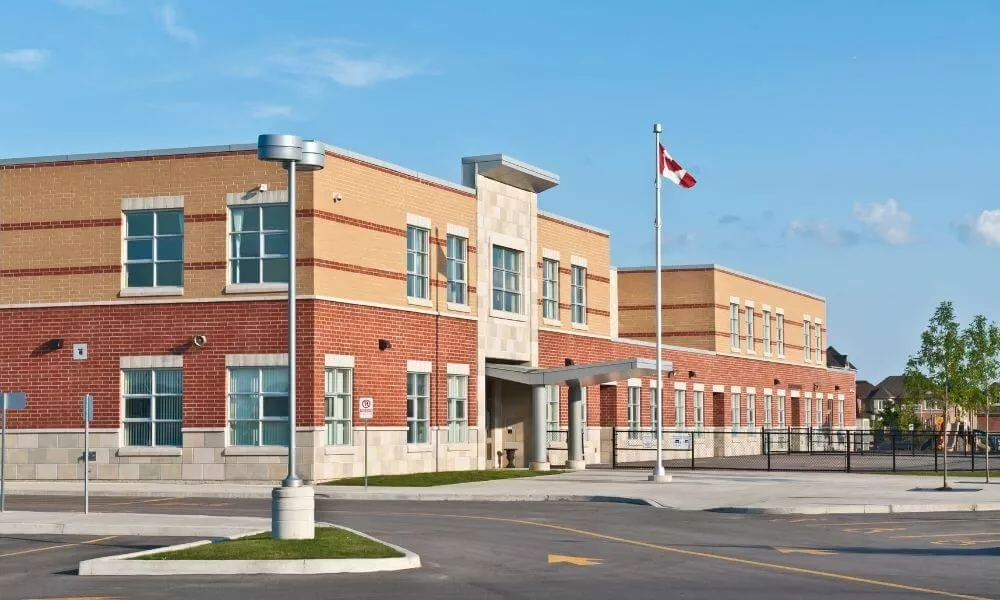 A school building with a flag pole and a parking lot