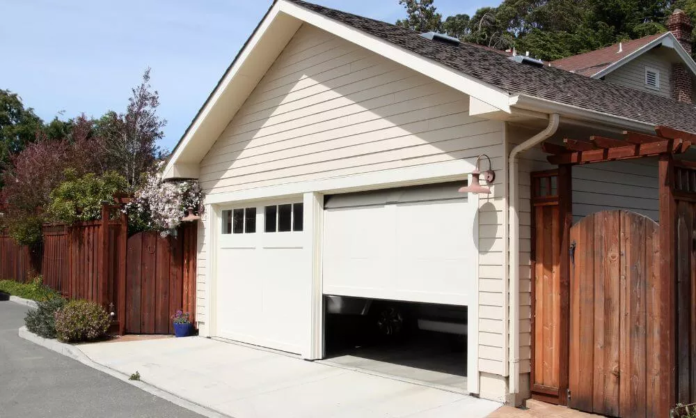 A white garage door with a wooden fence in the background