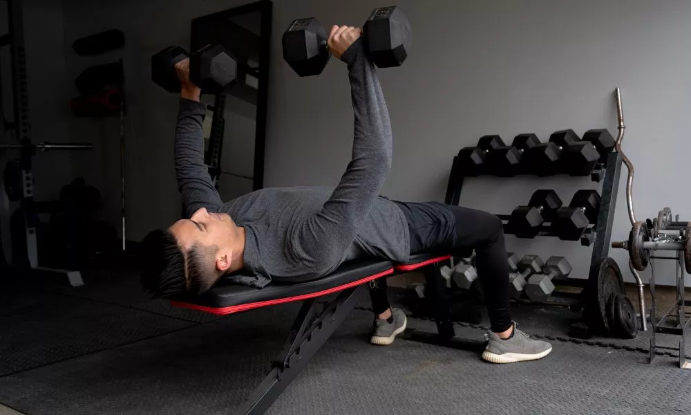 Lying man on a beanch doing weights
