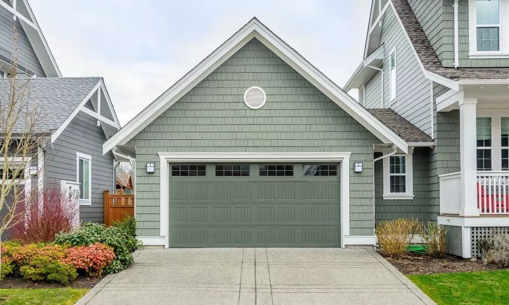 Green house with green double garage door with windows