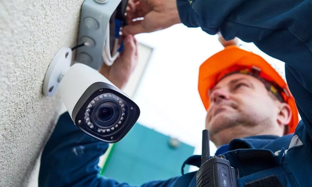 Man installing a camera on an outside wall