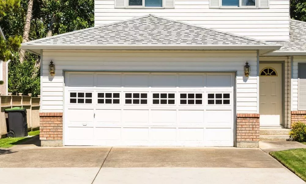 White garage door with 8-pane windows on a vinyl and brick house
